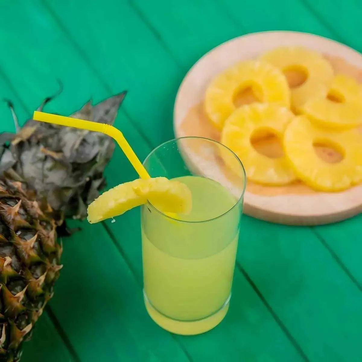 Verre de Soda ananas TOP avec tranche d’ananas frais, boisson pétillante jaune servie avec paille, parfaite pour une pause exotique.